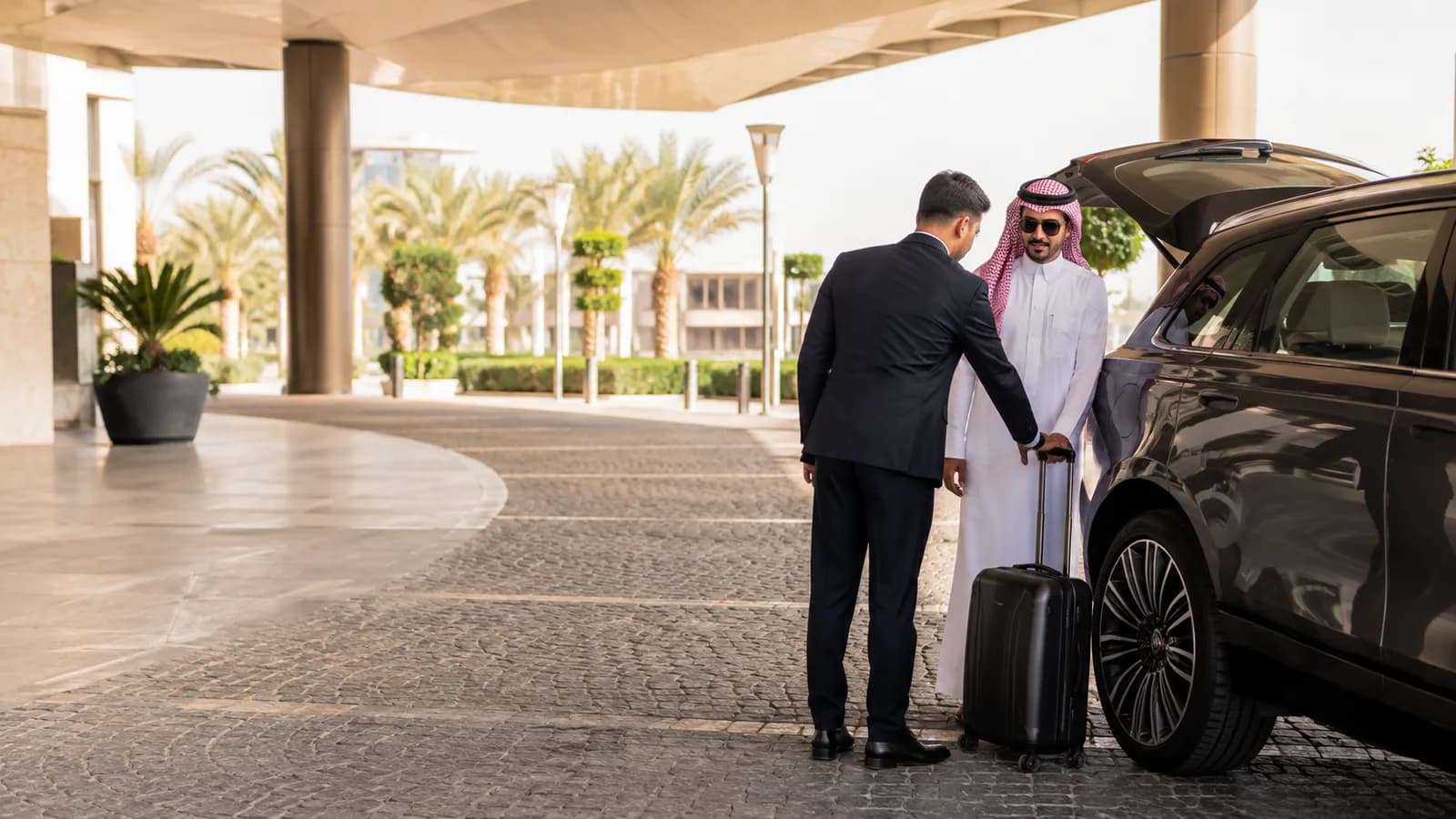 Gulf Trip Service chauffeur assisting a guest with luggage at a hotel entrance